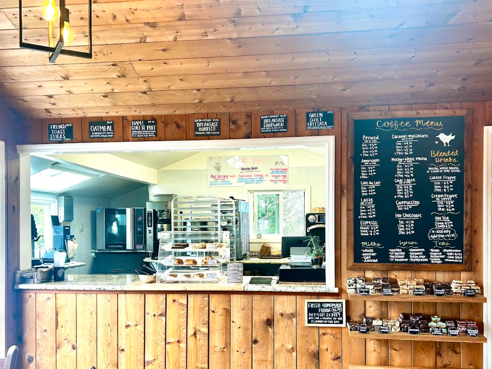 Interior of The Birds Cafe coffee shop counter with hand-lettered chalkboard menu and pastry case