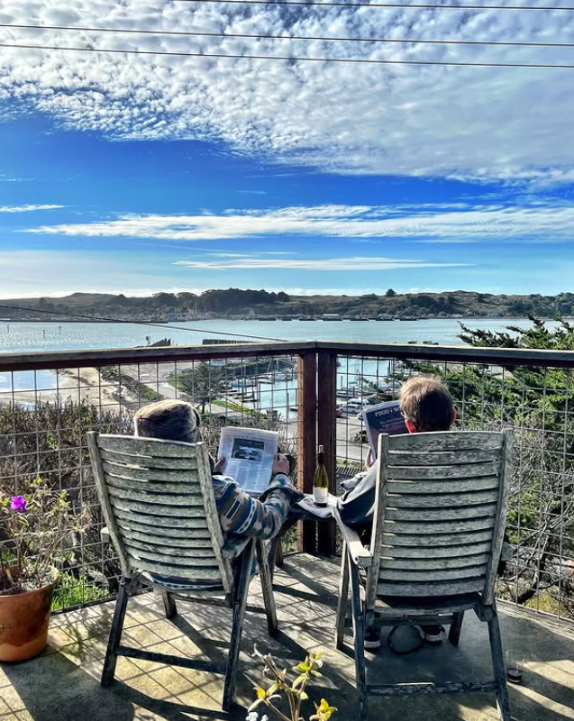 Two guests relaxing on the patio with wine, overlooking Bodega Bay