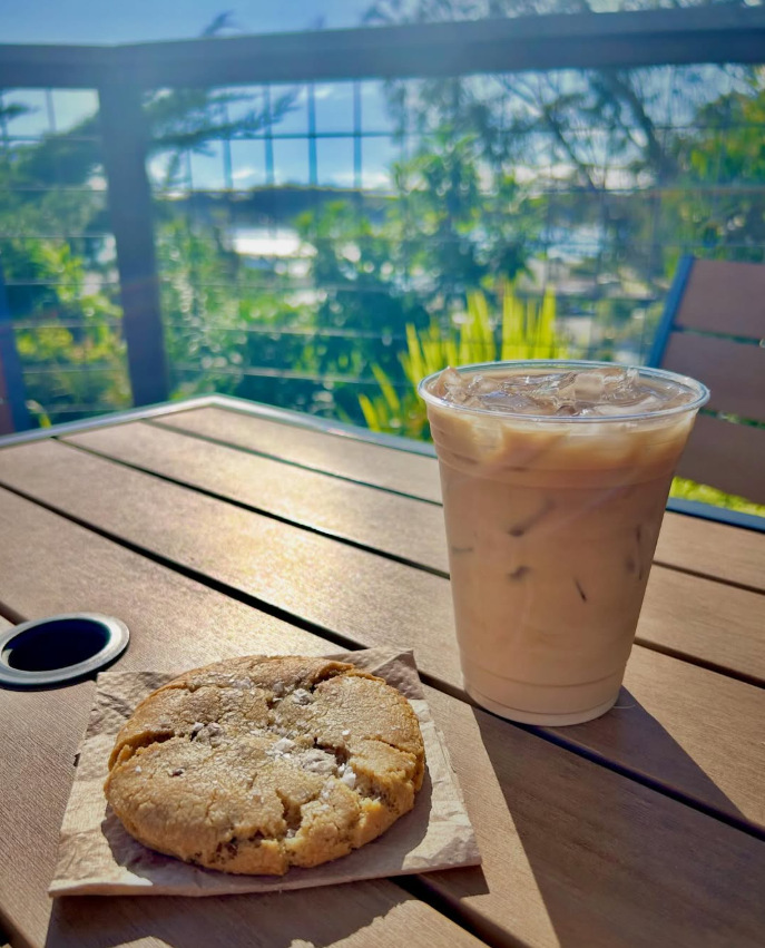 Iced latte and fresh cookie on a sunny patio table overlooking the bay